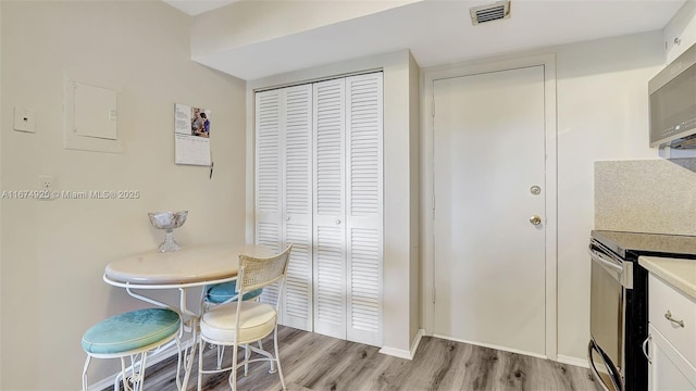 kitchen featuring stainless steel microwave, light wood-style flooring, range with electric stovetop, and visible vents