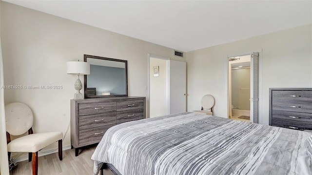 bedroom featuring light wood-type flooring, baseboards, visible vents, and connected bathroom