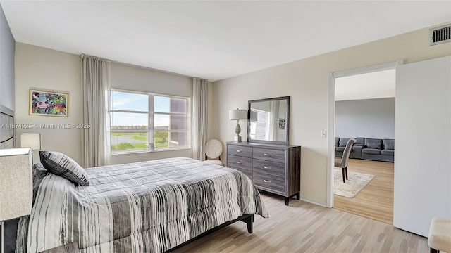 bedroom with light wood-style floors and visible vents