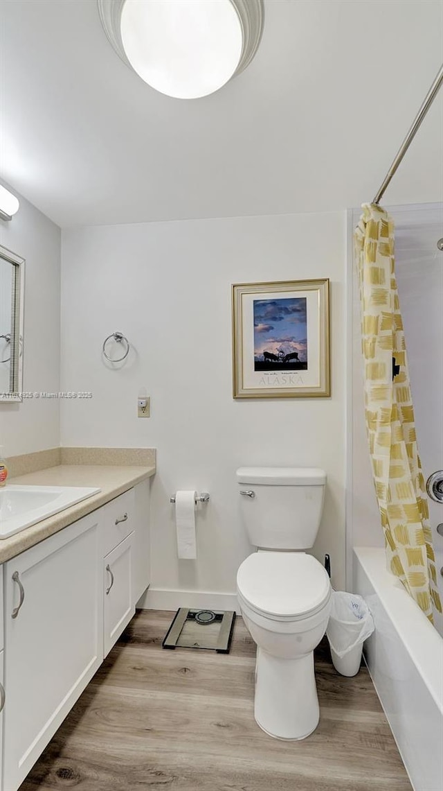 bathroom with shower / bathtub combination with curtain, vanity, toilet, and wood finished floors