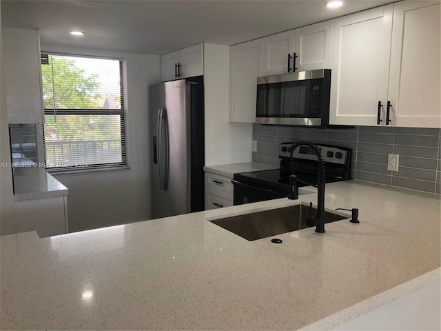 kitchen with white cabinets, light stone countertops, appliances with stainless steel finishes, and tasteful backsplash