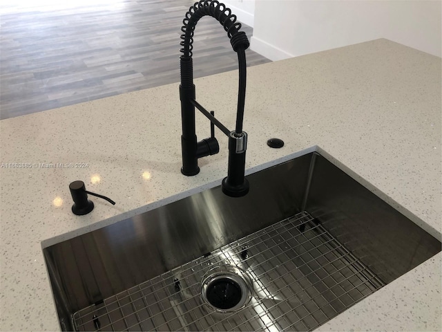 interior details featuring tasteful backsplash, sink, and hardwood / wood-style flooring