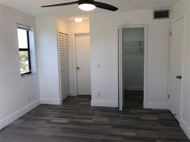 unfurnished bedroom featuring a textured ceiling, dark hardwood / wood-style flooring, a closet, and ceiling fan