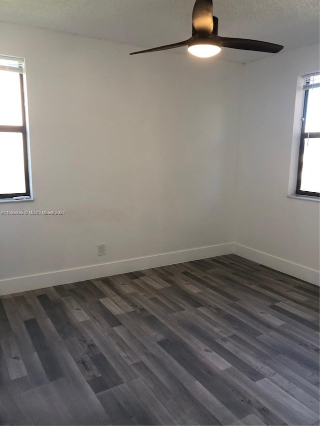 unfurnished room featuring dark hardwood / wood-style floors, ceiling fan, a textured ceiling, and a wealth of natural light