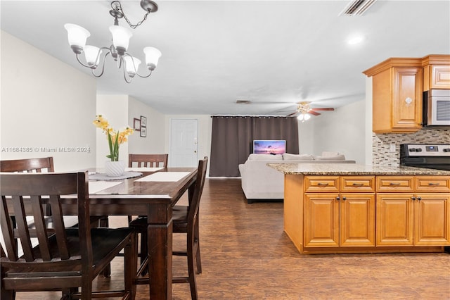 kitchen with light stone countertops, ceiling fan with notable chandelier, backsplash, stainless steel range oven, and dark hardwood / wood-style floors