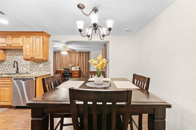 dining area featuring sink and ceiling fan with notable chandelier