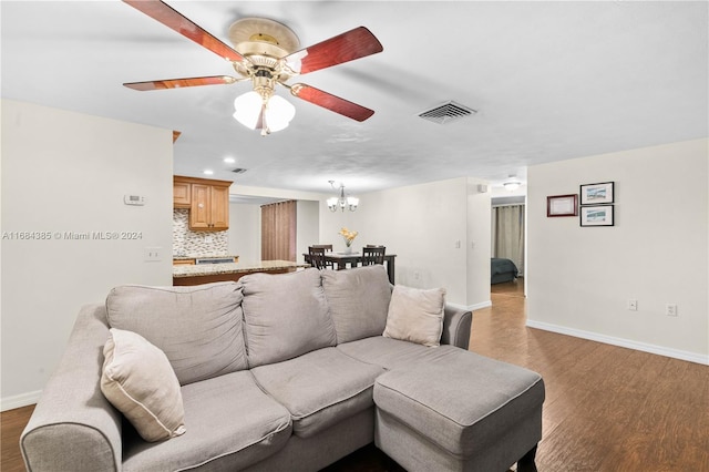 living room with ceiling fan with notable chandelier and dark hardwood / wood-style flooring