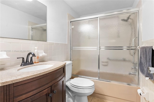 full bathroom with vanity, toilet, tile walls, and enclosed tub / shower combo