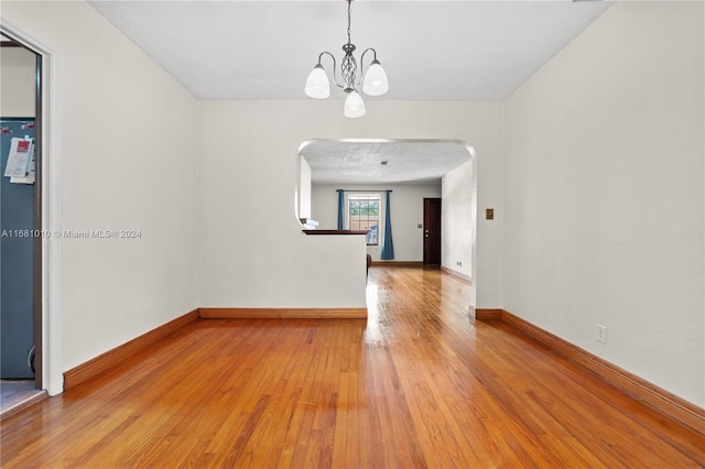 unfurnished room featuring a notable chandelier and hardwood / wood-style flooring