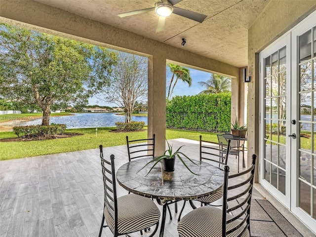 sunroom featuring a water view and ceiling fan