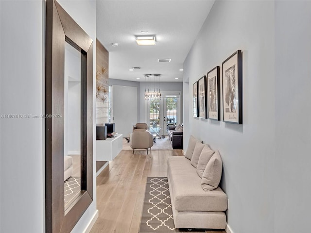 hall featuring french doors, a textured ceiling, and light wood-type flooring