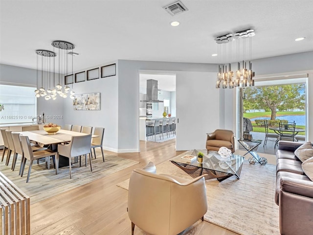 living room featuring a water view, a notable chandelier, and light hardwood / wood-style flooring