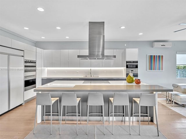 kitchen featuring a large island, extractor fan, paneled refrigerator, and a kitchen breakfast bar