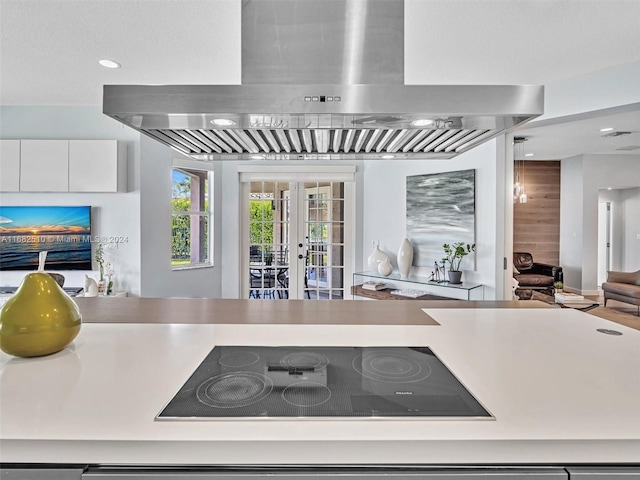 kitchen with french doors, black electric cooktop, ventilation hood, and white cabinets