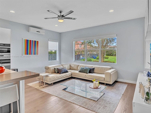 living room with ceiling fan, light wood-type flooring, and a wall unit AC