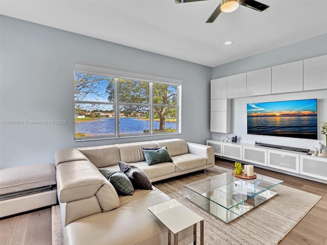 living room featuring baseboard heating, hardwood / wood-style floors, and ceiling fan