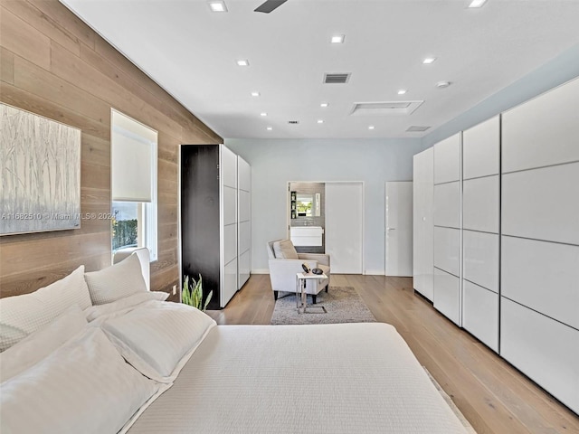 bedroom with light hardwood / wood-style floors and wooden walls