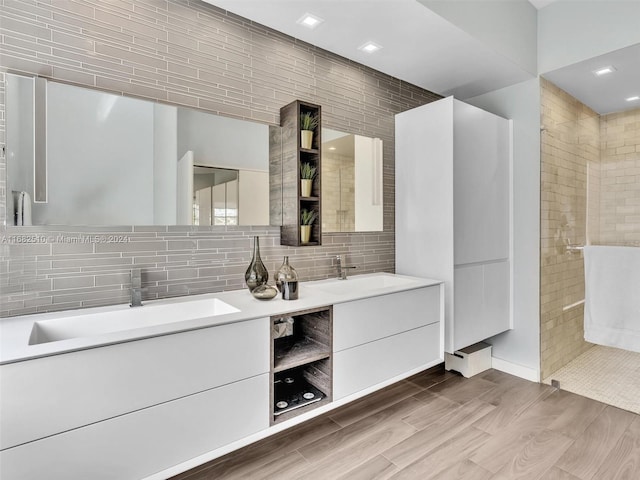 bathroom with vanity, decorative backsplash, tiled shower, and hardwood / wood-style floors