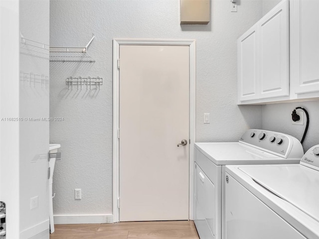 clothes washing area featuring cabinets, washing machine and dryer, and light wood-type flooring