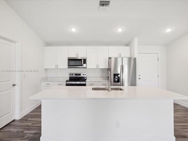 kitchen with white cabinetry, stainless steel appliances, an island with sink, and dark hardwood / wood-style floors