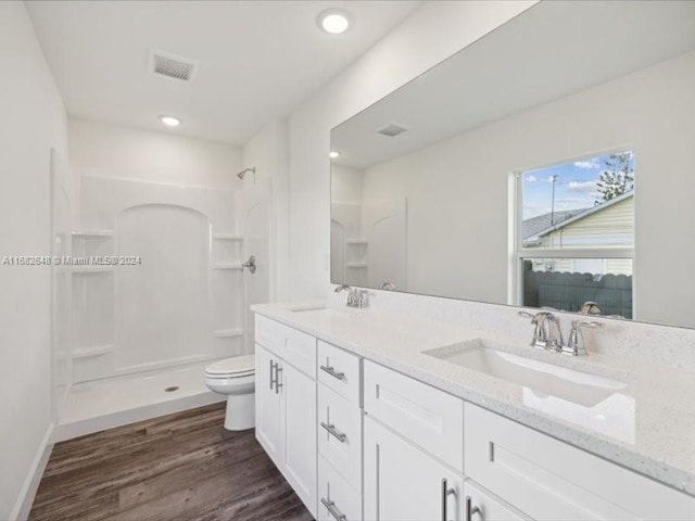 bathroom featuring vanity, hardwood / wood-style flooring, toilet, and walk in shower