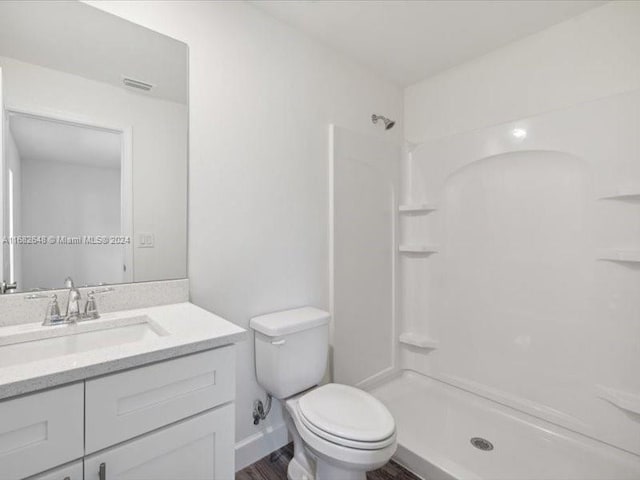 bathroom with vanity, toilet, a shower, and hardwood / wood-style floors