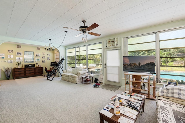 carpeted living room featuring a healthy amount of sunlight and ceiling fan with notable chandelier