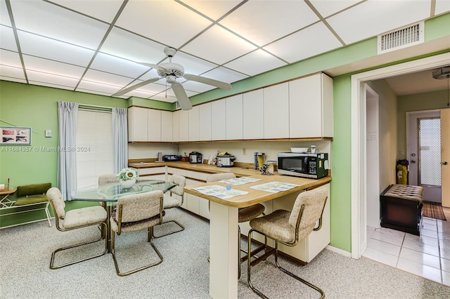 dining space featuring a paneled ceiling, light tile patterned flooring, and ceiling fan