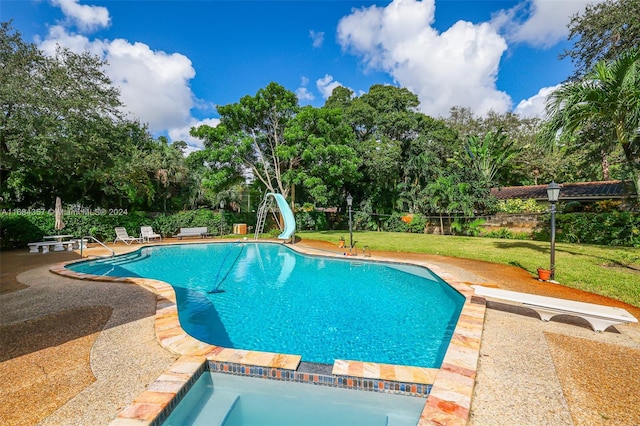 view of swimming pool with a yard, a water slide, and a diving board