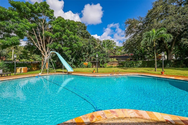 view of swimming pool with a yard and a water slide