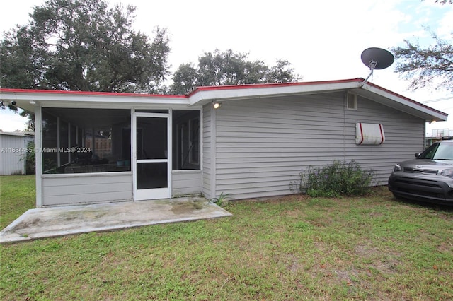 rear view of property featuring a lawn and a sunroom