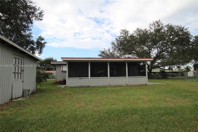 rear view of property with a lawn and a sunroom