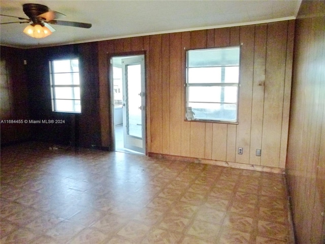 empty room featuring wood walls and ceiling fan