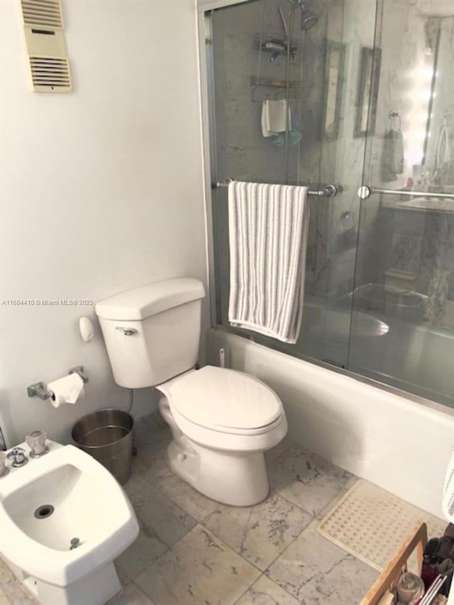 bathroom featuring a bidet, enclosed tub / shower combo, and toilet