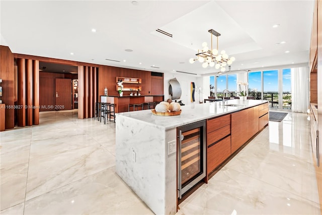 kitchen with sink, beverage cooler, a tray ceiling, a spacious island, and hanging light fixtures