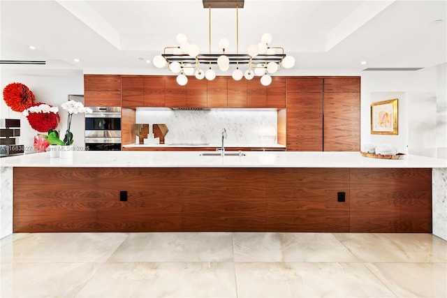 kitchen with a chandelier, sink, pendant lighting, stainless steel double oven, and a raised ceiling