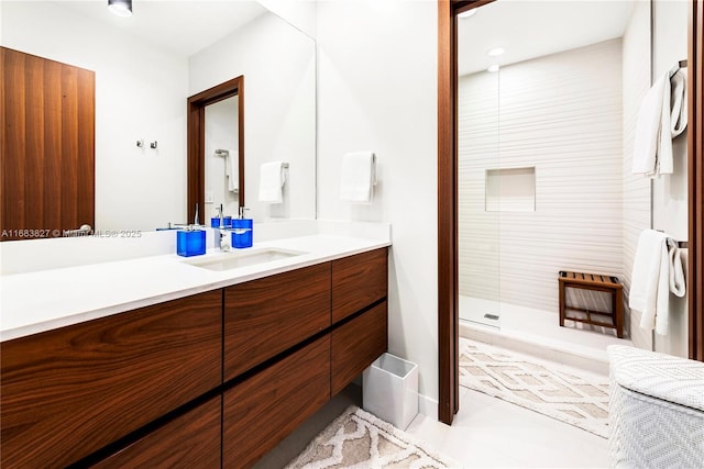 bathroom with tiled shower and vanity