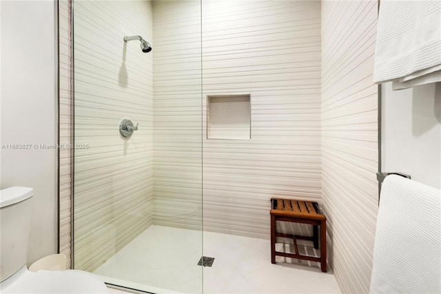 bathroom featuring tiled shower and toilet