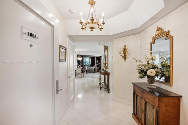 corridor with light tile patterned flooring and a chandelier