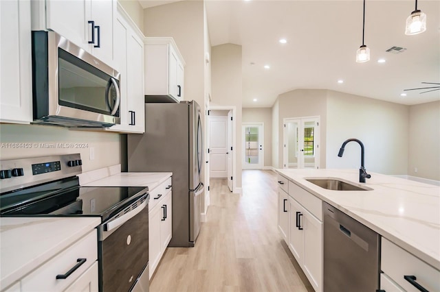 kitchen featuring white cabinetry, vaulted ceiling, sink, pendant lighting, and stainless steel appliances