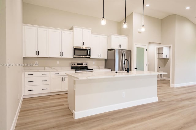 kitchen with appliances with stainless steel finishes, white cabinets, decorative light fixtures, and a center island with sink