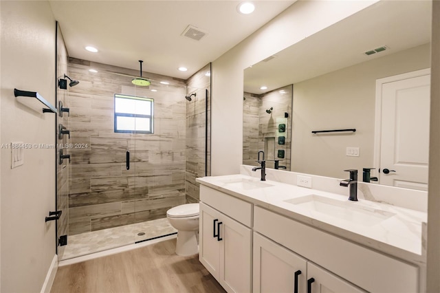 bathroom with toilet, hardwood / wood-style floors, vanity, and a shower with door