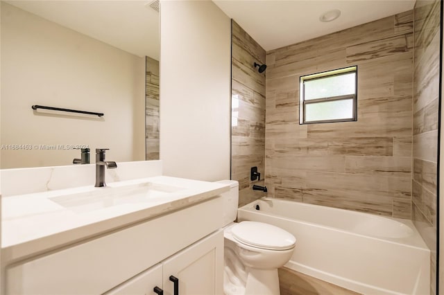 full bathroom featuring vanity, tiled shower / bath, and toilet