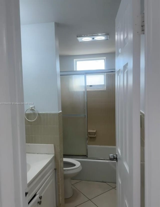 full bathroom with toilet, bath / shower combo with glass door, vanity, and tile patterned floors