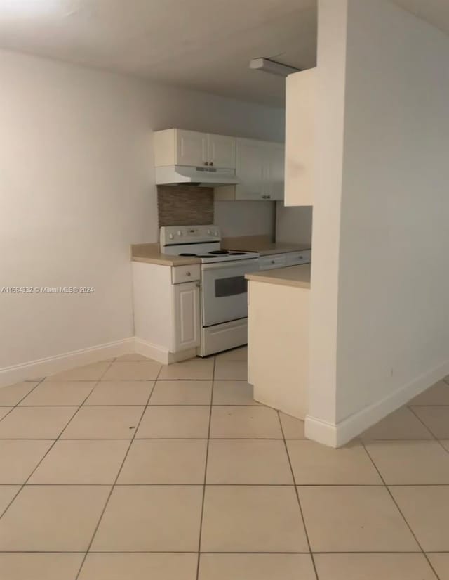 kitchen with backsplash, light tile patterned floors, white range with electric cooktop, and white cabinets