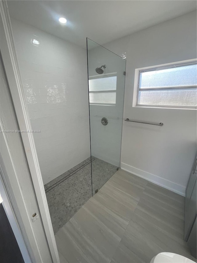 bathroom featuring tiled shower and toilet