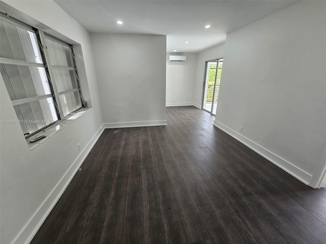 unfurnished room with a wall mounted AC and dark hardwood / wood-style flooring