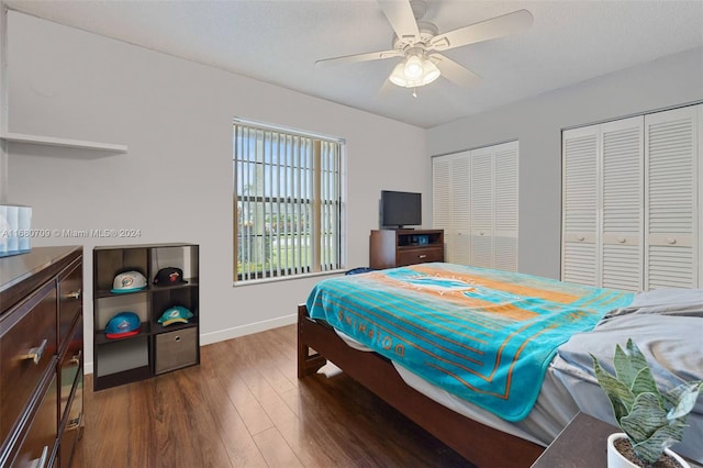 bedroom featuring ceiling fan, a textured ceiling, multiple closets, and dark hardwood / wood-style flooring