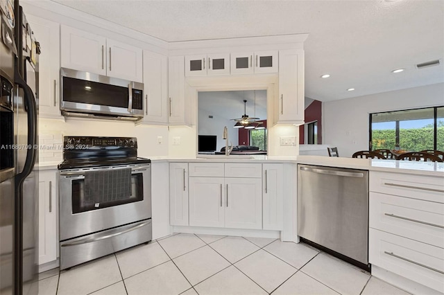 kitchen with appliances with stainless steel finishes, ceiling fan, white cabinets, and light tile patterned floors