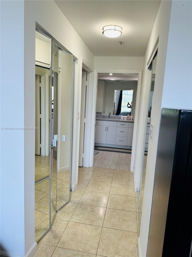 corridor featuring light tile patterned flooring and sink